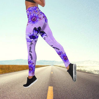 Vibrant purple floral yoga pants with a high-waist design, worn by a person standing on a road surrounded by a scenic outdoor landscape.