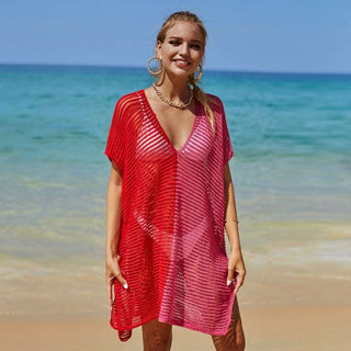 Vibrant red knit beach coverup with plunging neckline, worn by a smiling woman against an ocean backdrop