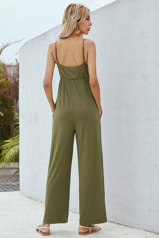 Olive green wide-leg jumpsuit with a cinched waist, showcased against a plain white wall backdrop.