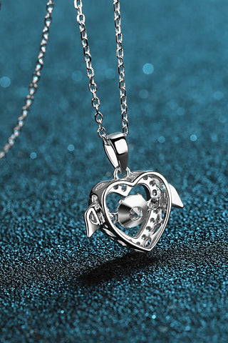Elegant sterling silver heart-shaped pendant necklace with sparkling moissanite stone, set against a shimmering teal background.