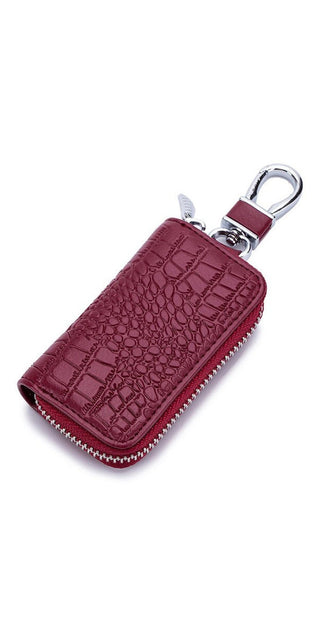 Compact leather key holder in burgundy with crocodile texture, featuring a zipper closure and metal clasp for convenient key storage and organization.