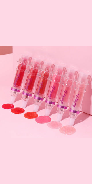 Assortment of vibrant, glossy lip colors in tubes on a pastel pink background