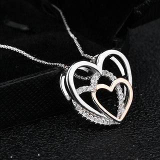 Elegant silver heart-shaped pendant necklace with sparkling rhinestone accents, displayed on a black background. This fine jewelry piece features interlocking hearts design, capturing the essence of love and affection.