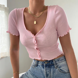 Stylish pink ruffled crop top with short sleeves, paired with denim jeans and gold chain necklace.