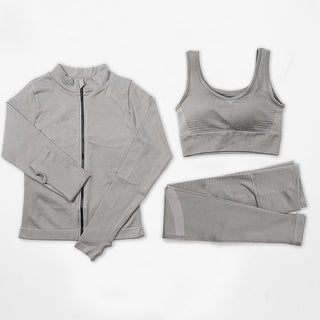 Seamless sportswear set including grey zip-up jacket, sports bra and leggings on plain white background.