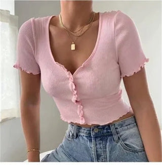 Ribbed pink crop top with ruffle details, worn with gold necklaces and high-waisted denim jeans, showcasing a stylish and trendy casual look.