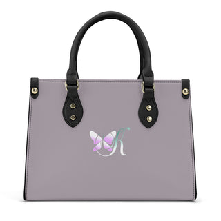 Elegant gray leather handbag with a stylish butterfly emblem, featuring dual black handles and accents for a sophisticated, fashionable look.