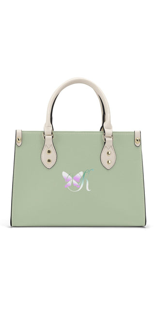 Elegant green leather handbag with white handles and metal hardware, featuring a butterfly emblem design, displayed on a plain white background.