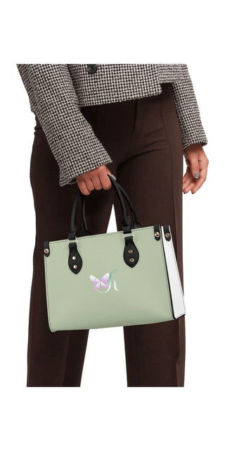 Stylish mint green handbag with a sleek design and contrasting black handles, carried by the person wearing a houndstooth blazer.