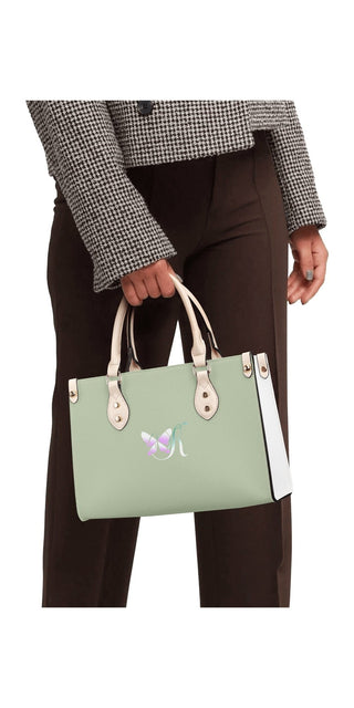 Stylish mint green leather handbag with white accents and a simple, modern design carried by a woman wearing a black and white houndstooth pattern blazer.
