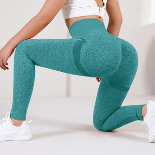Teal-colored yoga leggings with a textured, sculpting design showcased on a woman's lower body against a white background.