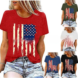 Patriotic women's graphic t-shirt featuring an American flag design with distressed stars and stripes, available in various colors. The shirt is worn by a young blonde woman posing against a plain background.