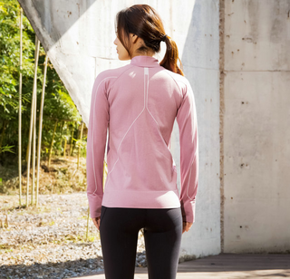 Slim fit sports jacket in soft pink color, showcased on a woman standing in an outdoor setting with a concrete wall and nature elements in the background.
