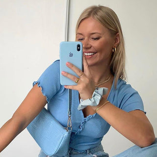 Smiling woman in blue top taking selfie with smartphone