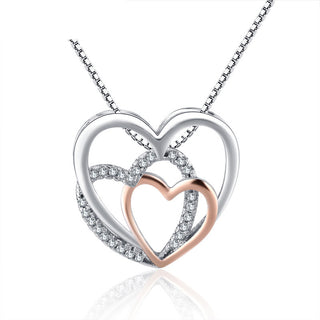 Elegant heart-shaped pendant necklace with shimmering crystal accents, showcased on a delicate silver-toned chain. The intricate design features a rose gold-toned heart nestled within a larger silver-toned heart, creating a chic, feminine look perfect for everyday wear or special occasions.
