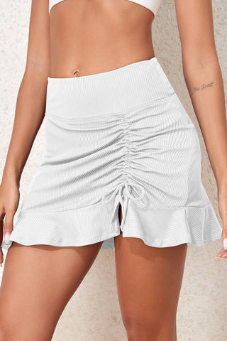 Stylish white ruched swim skirt with an elastic waistband, featured against a plain background.