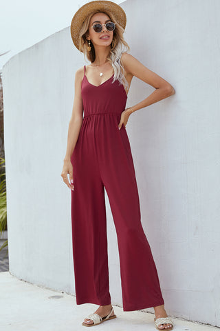 Fashionable burgundy jumpsuit, elegant summer style, straw hat, trendy sunglasses, comfortable sandals, woman posing on bright white background.