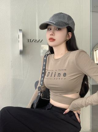 Trendy, casual woman's apparel: cropped beige top with text graphics, adjustable gray cap, and sleek black pants.