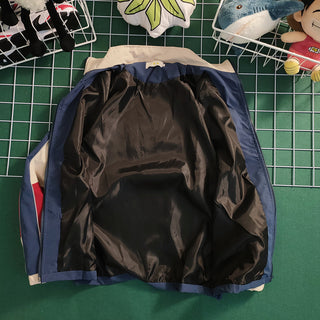 Retro color contrast patchwork baseball jacket on a green background with craft supplies.