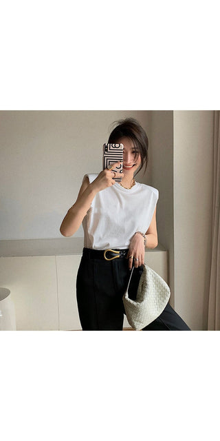 Stylish sleeveless white t-shirt, black pants, stylish accessory, minimalist decor.