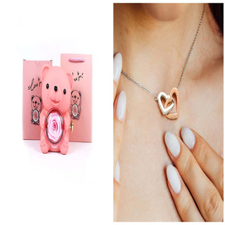 Rotating eternal flower ring necklace packaging box in pink gift boxes with heart-shaped pendant necklace against female hand with painted nails.