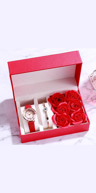 Stylish Valentine's Day gift set: Elegant women's watch, rose bouquet, and jewelry box in a vibrant red gift box on a marble surface.