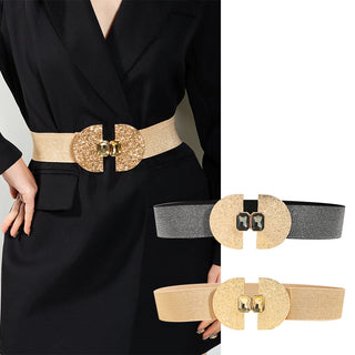 Elegant glittering gold and black elastic belts with decorative buckle accents, worn with a stylish black dress, creating a chic and polished fashion look.