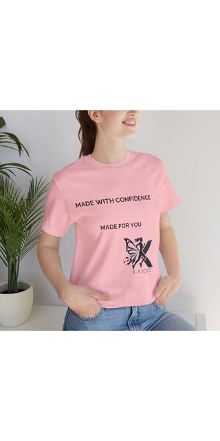 Unisex casual pink t-shirt with text "Made with Confidence, Made for You" and butterfly graphic design, worn by a woman against a white background with potted plants.