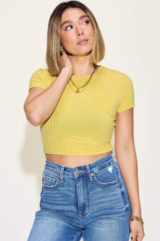 Stylish ribbed yellow crop top on young woman posing against neutral background