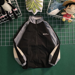 Retro color contrast patchwork baseball jacket with black and grey accents displayed on a grid background with plush toys.