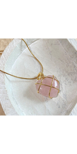 Elegant Rose Quartz Pendant Necklace
A beautiful rose quartz gemstone encased in a delicate gold-toned wire design, hanging gracefully on a thin metallic chain against a smooth, marble-like backdrop.