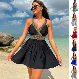 Elegant beach attire: A black summer dress with a V-neck and geometric print accents, worn by a woman on a sunny beach with a scenic ocean backdrop.
