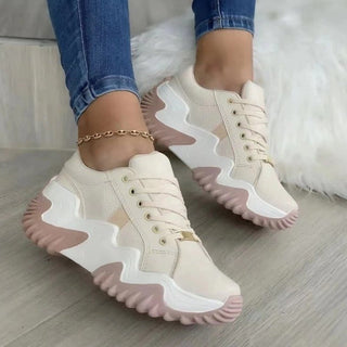 Trendy white women's sneakers with chunky soles and lace-up closure, placed on a soft, fluffy white rug.