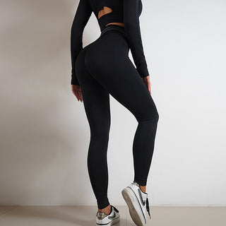 Stylish athletic leggings and top in black with cutout design, worn by a female model against a neutral background.