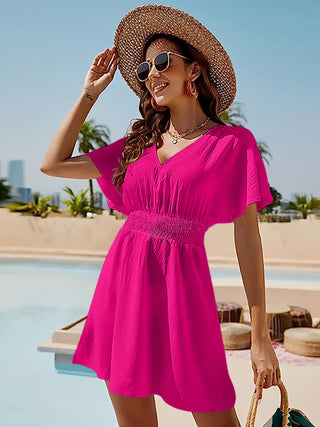 Fashionable pink mini dress with puffy sleeves, straw hat, and sunglasses on a woman by the pool
