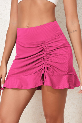 Vibrant pink swim skirt with ruched elastic waistband and ruffled hem, showcasing a stylish and flattering silhouette.