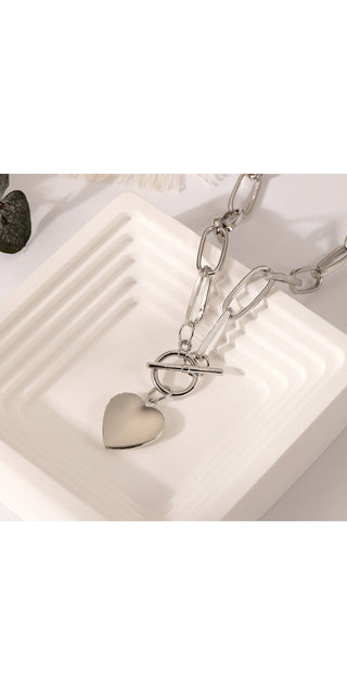 Elegant silver-toned heart-shaped pendant necklace with ornate chain design, displayed on a white background.