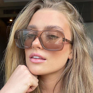 Trendy oversized square sunglasses with large rims on the face of a young woman.