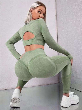 Seamless green sportswear set with long sleeve crop top and high-waist leggings, featuring a stylish cutout detail and comfortable fit for an active lifestyle.