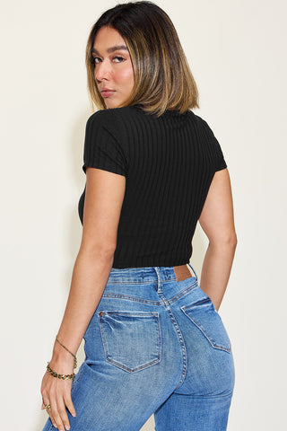 Sophisticated ribbed black short sleeve top worn by a young woman against a plain white background.