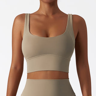 Beige sports bra with supportive straps, perfect for yoga, fitness, or everyday wear. The nude-colored fabric provides a comfortable, smooth feel while the design offers shockproof support during physical activities.