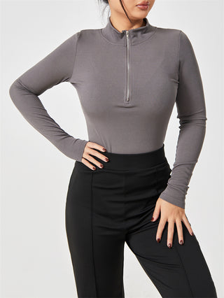 Stylish gray zip-up bodysuit with long sleeves, worn by a woman against a plain background.
