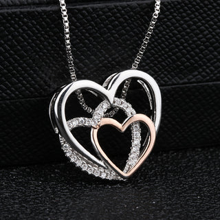 Elegant overlapping heart-shaped pendant necklace with sparkling crystal accents, displayed on a black leather-like surface.