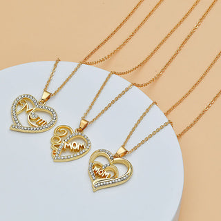 Heart-shaped necklaces with diamond-accented "Mom" and heart-shaped pendants on gold-toned chains, displayed on a white background against a beige surface. These elegant jewelry pieces are part of the K-AROLE women's fashion accessories collection, perfect as Mother's Day gifts or stylish everyday wear.