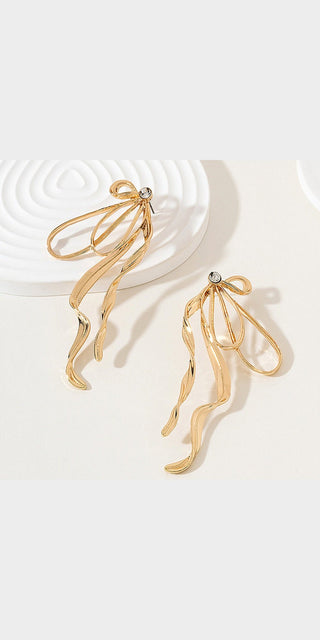 Elegant gold tone statement earrings with large bows and tasseled streamers, displayed on a white background.