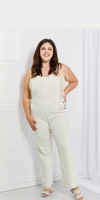 High-waist overalls showcased on smiling female model in bright, white studio setting