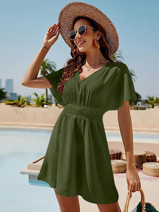Smiling woman in straw hat and sunglasses wearing olive green sundress near pool