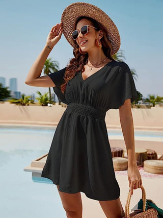 Stylish black sundress with puff sleeves, straw hat, and sunglasses against tropical backdrop