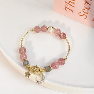 Elegant natural stone star and moon strawberry crystal bracelet with gold-tone charms and beads adorning a woman's wrist against a clean, white background.
