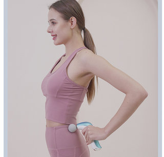 Attractive woman in pink sports bra and leggings using massage gun for deep tissue therapy